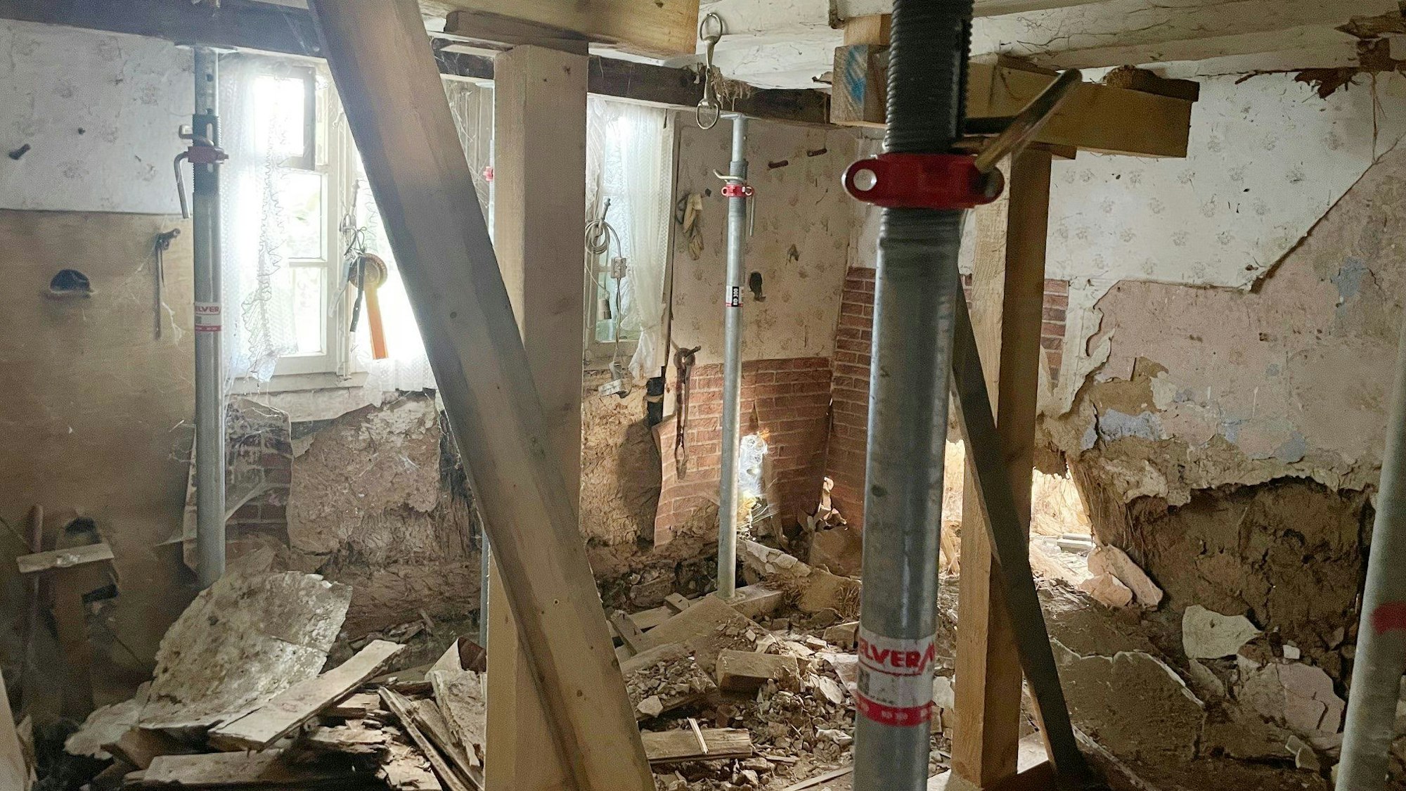 Das Bild zeigt einen Blick ins Fachwerkhaus. Der Putz ist von der Wand gefallen, zudem sind viele Stützen zu erkennen.