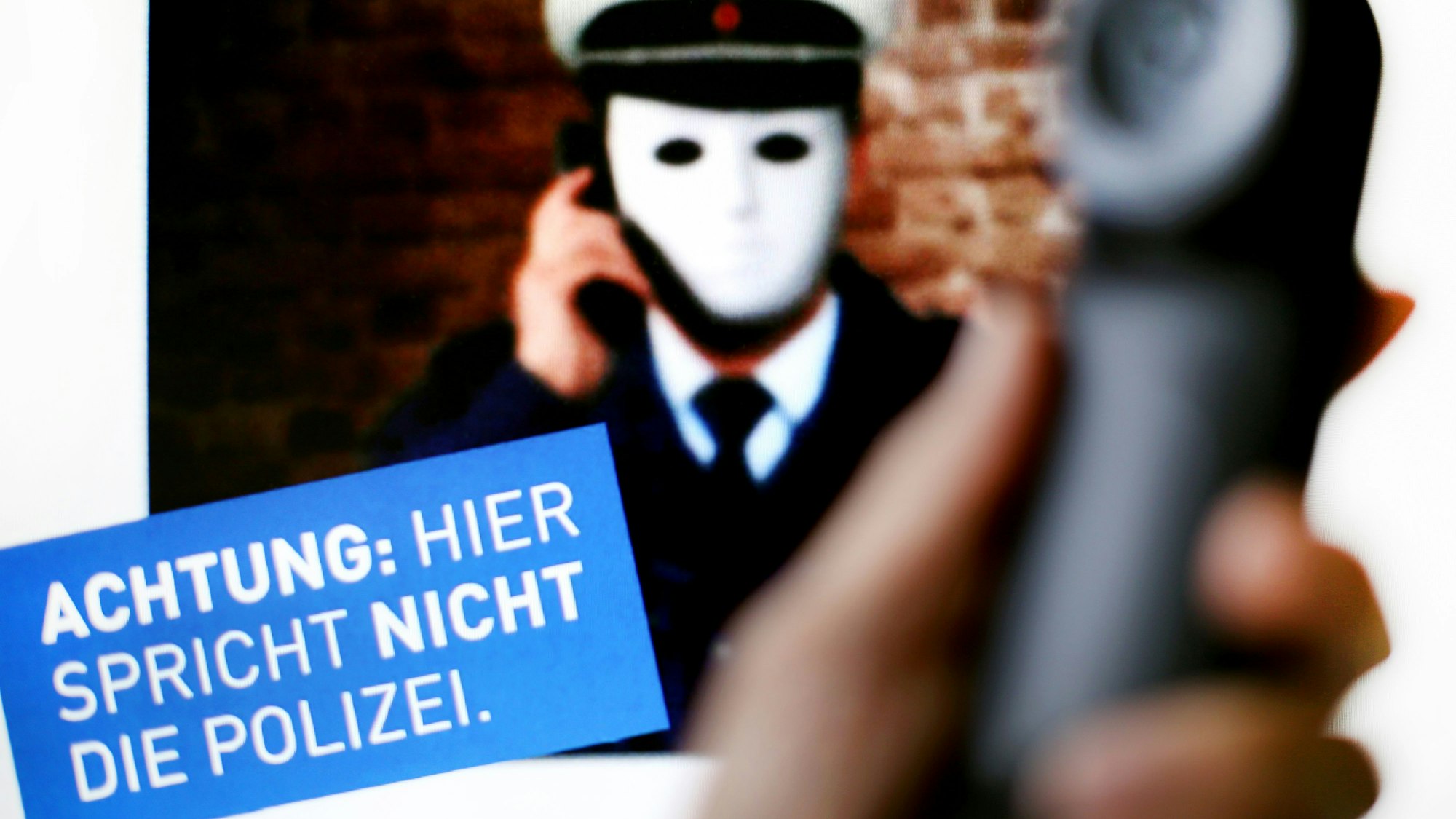 1.10.2017, Nordrhein-Westfalen, Düsseldorf: Ein Telefonhörer ist vor einem Plakat der Polizei NRW mit der Aufschrift «Achtung: Hier spricht nicht die Polizei» zu sehen.