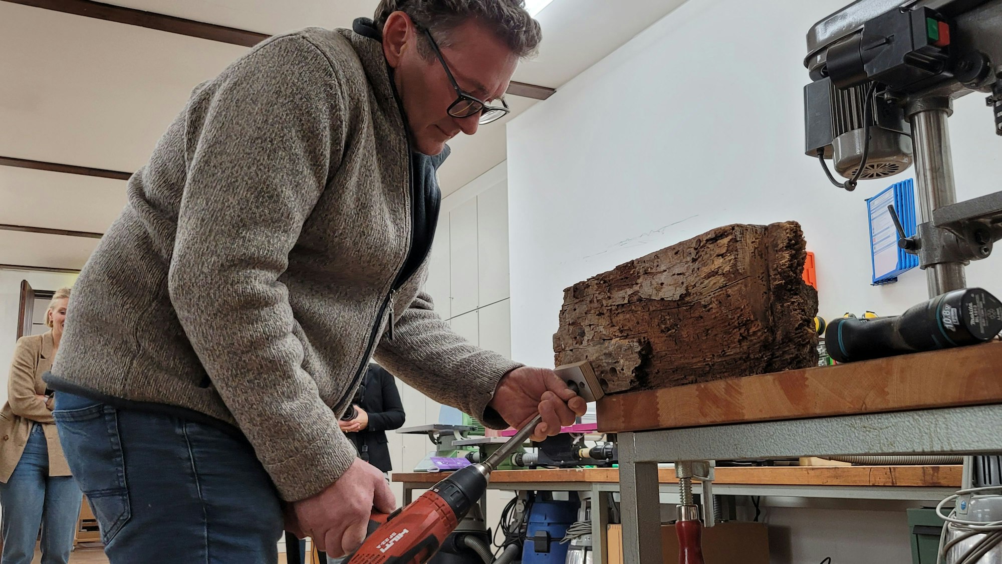 Ein Mann bohrt einen Holzbalken an.