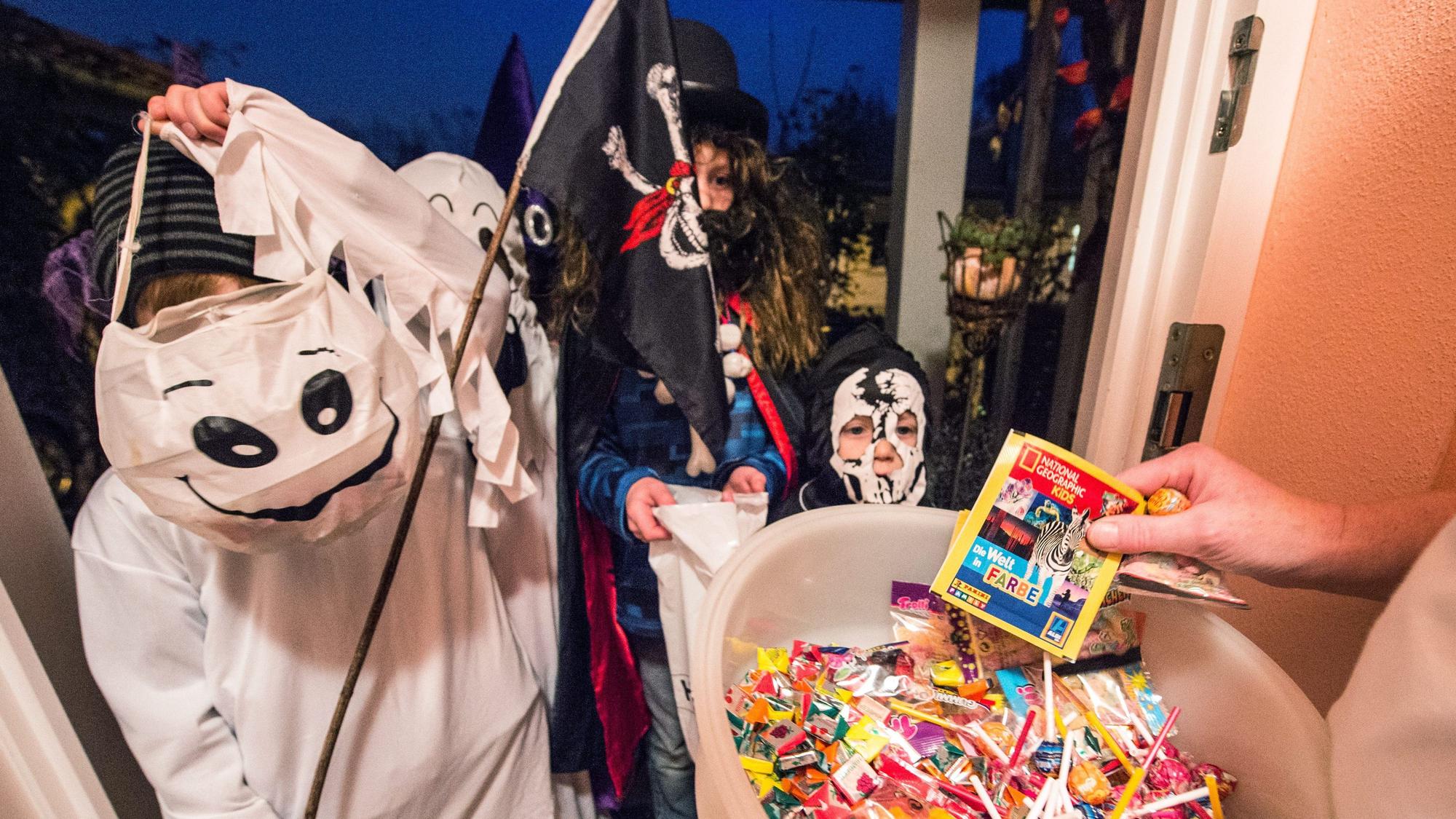 Zu Halloween ziehen Kinder von Haustür zu Haustür und freuen sich über süße Sachen.