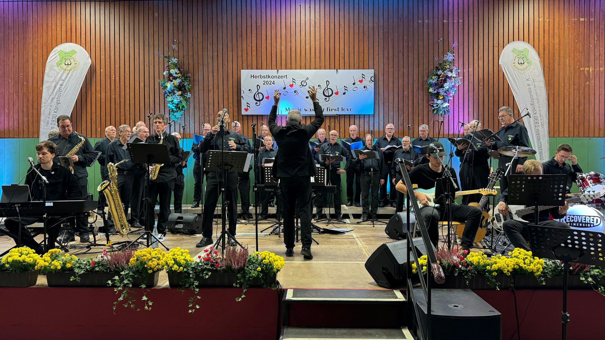 Ein Männerchor steht auf einer Bühne.