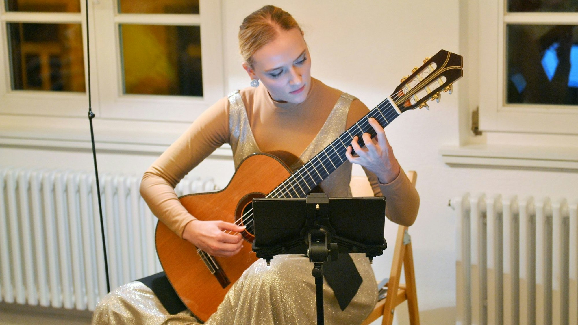 Eine Frau spielt Gitarre in einem Abendkleid.