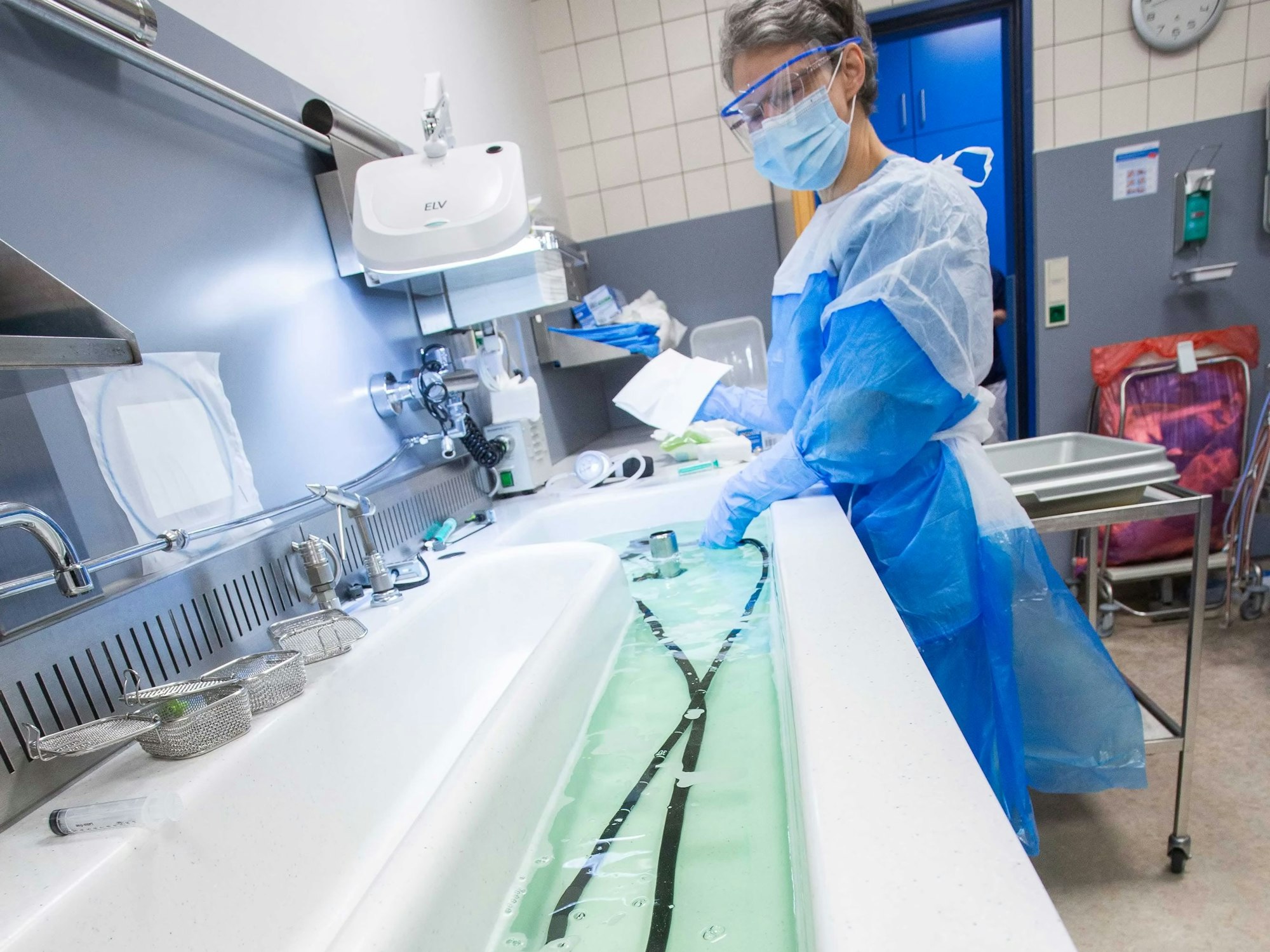 Ein benutztes Endoskop wird in einem Krankenhaus durch eine Frau in Schutzkleidung nach strengen Vorgaben gereinigt.
