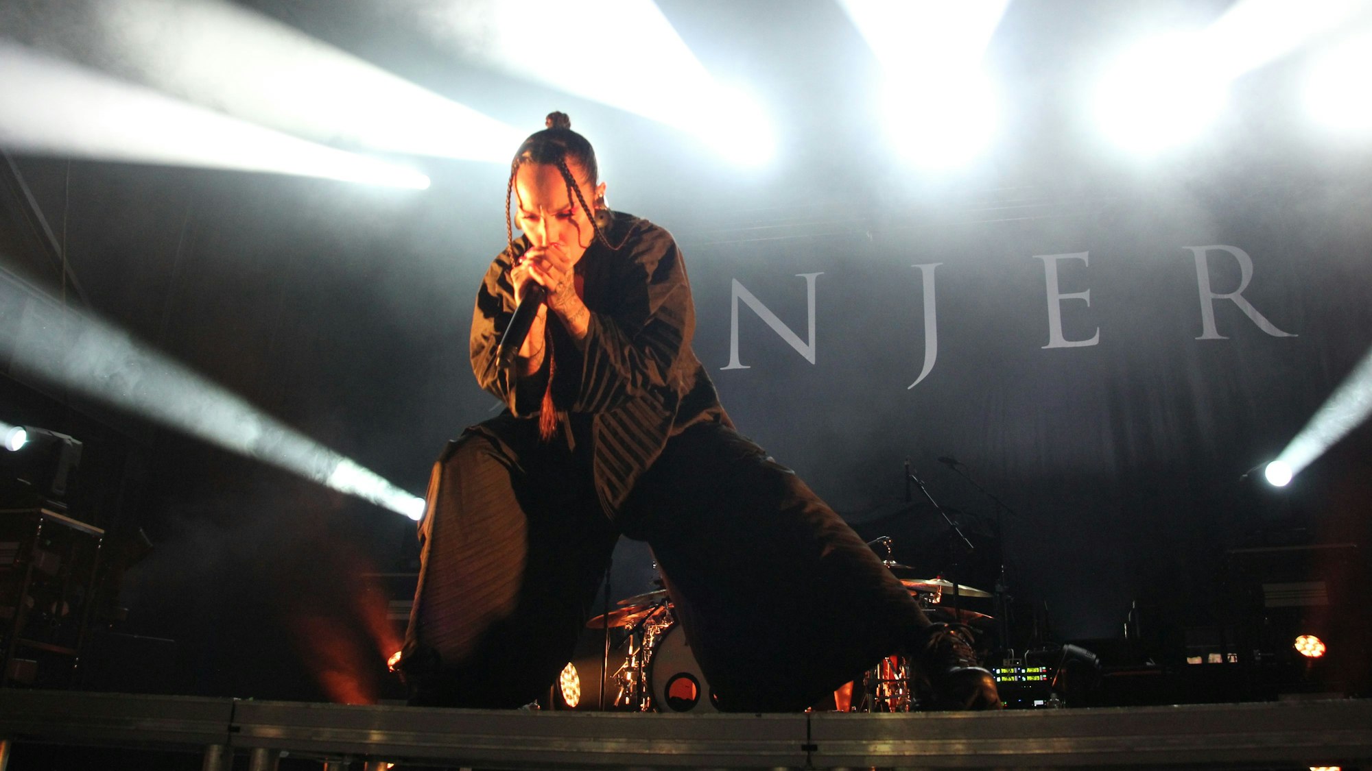 Eine Sängerin post mit dem Mikrofon vor dem Gesicht auf der Bühne.