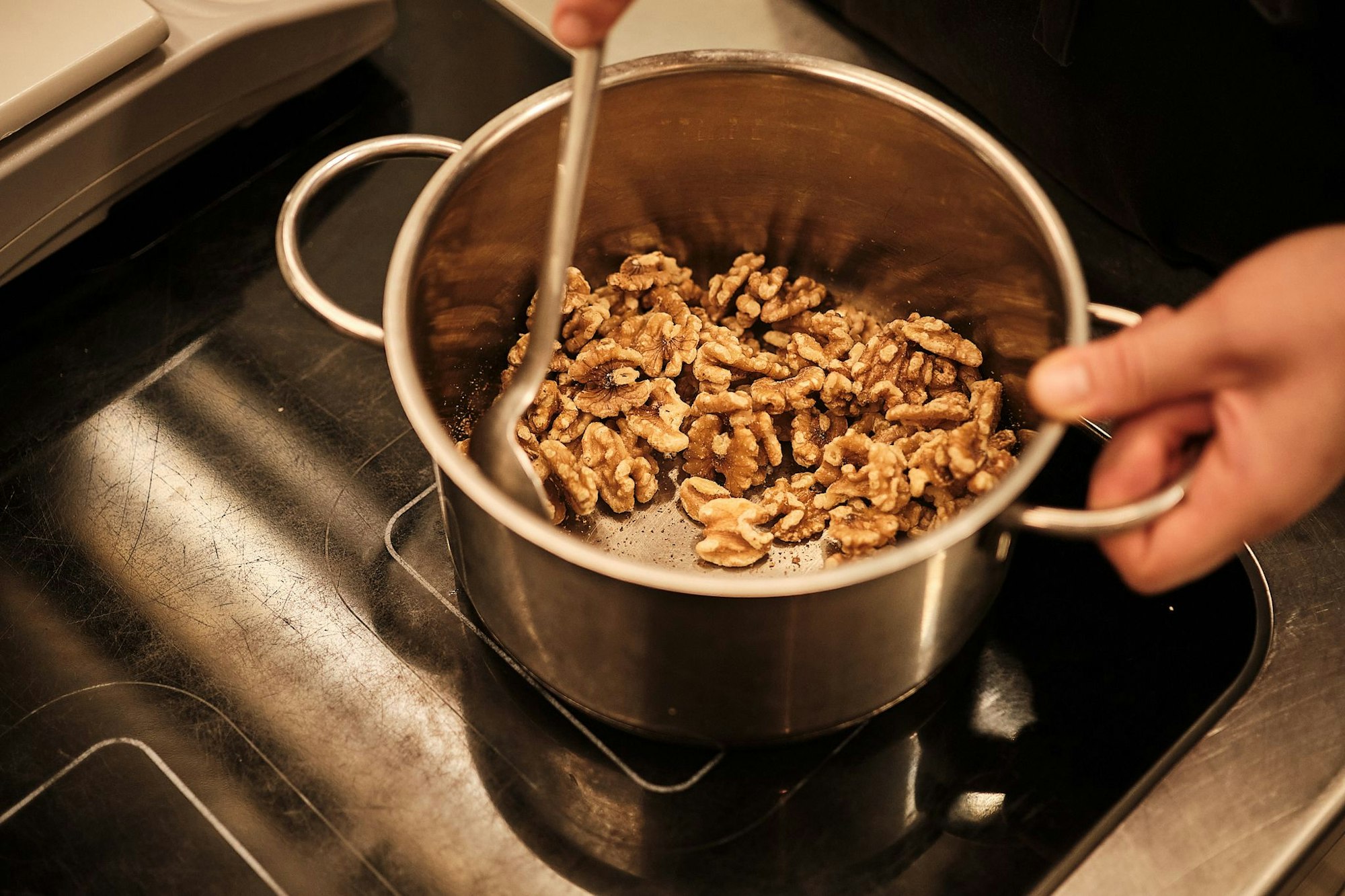 Zucker und Wasser in eine Pfanne geben und zum Kochen bringen. Sobald ein Großteil des Wassers verdampft ist, die Walnüsse zugeben.