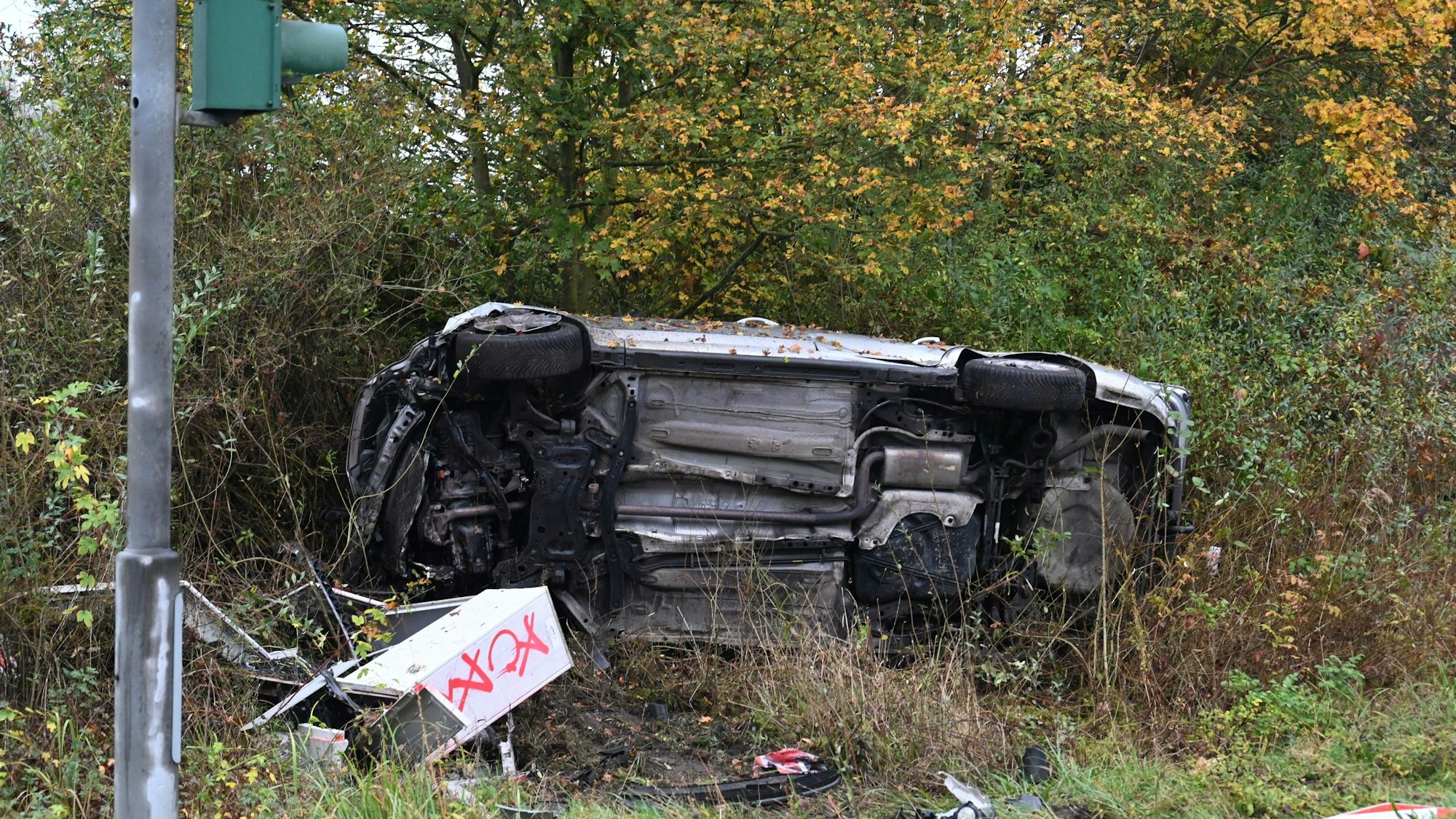 Ein Auto liegt auf der Seite neben der Straße im Grünstreifen.
