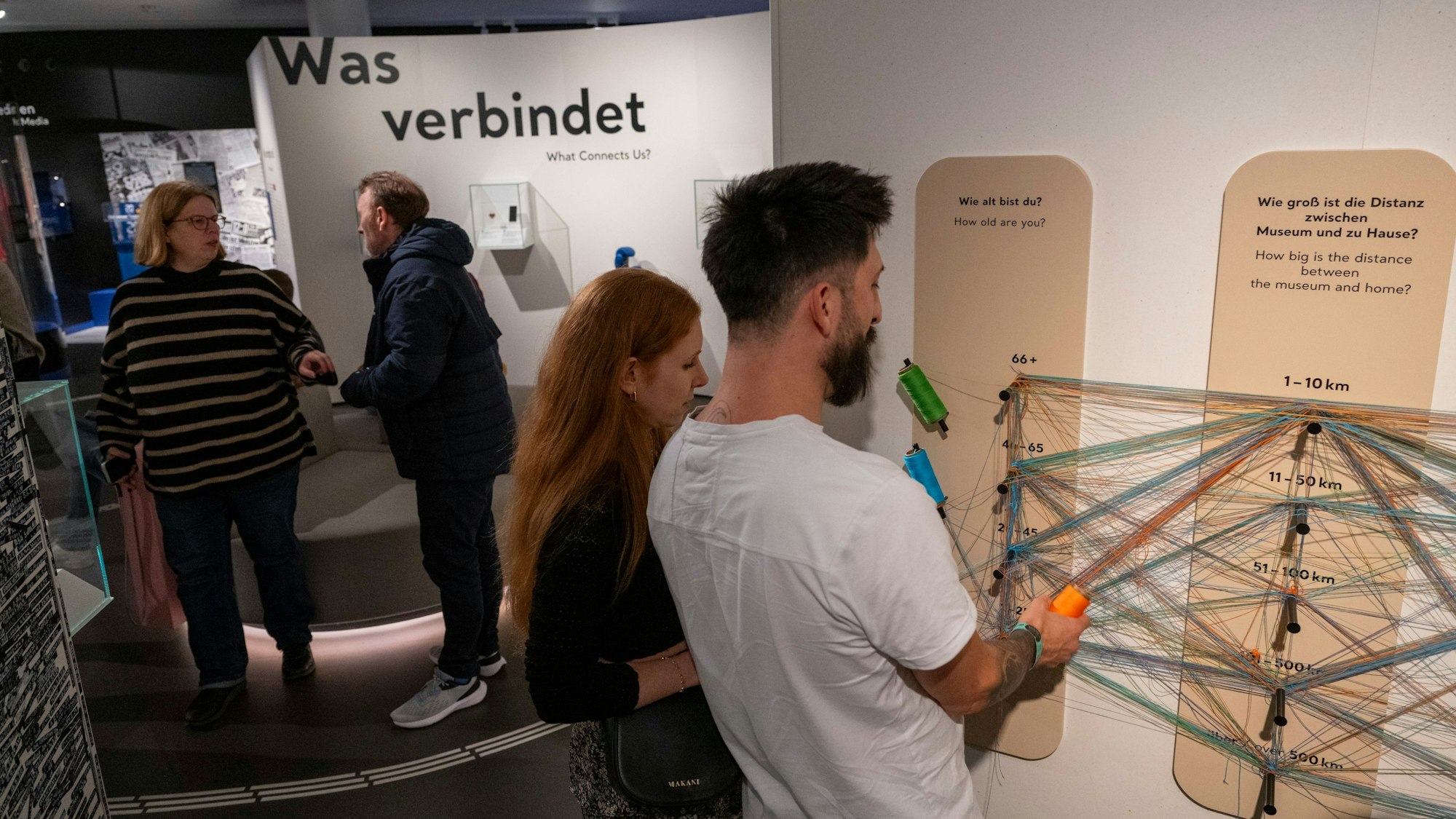 Besucher betrachten ein Board, auf dem Antworten mit Schüren verbunden werden.