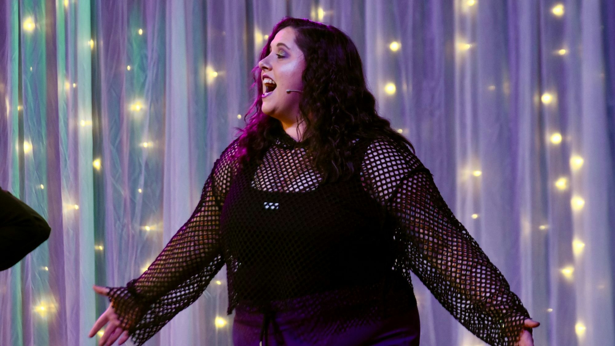 Eine Frau singt mit ausgebreiteten Armen.