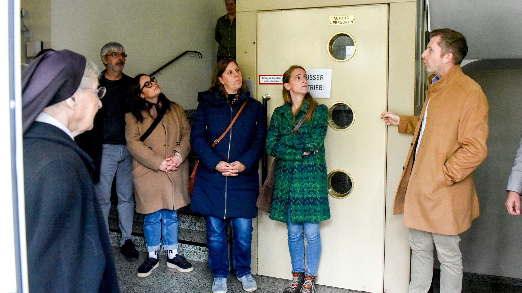 Ein Mann erläutert Besuchern im Inneren eines Hauses, was sich dort verändern soll.