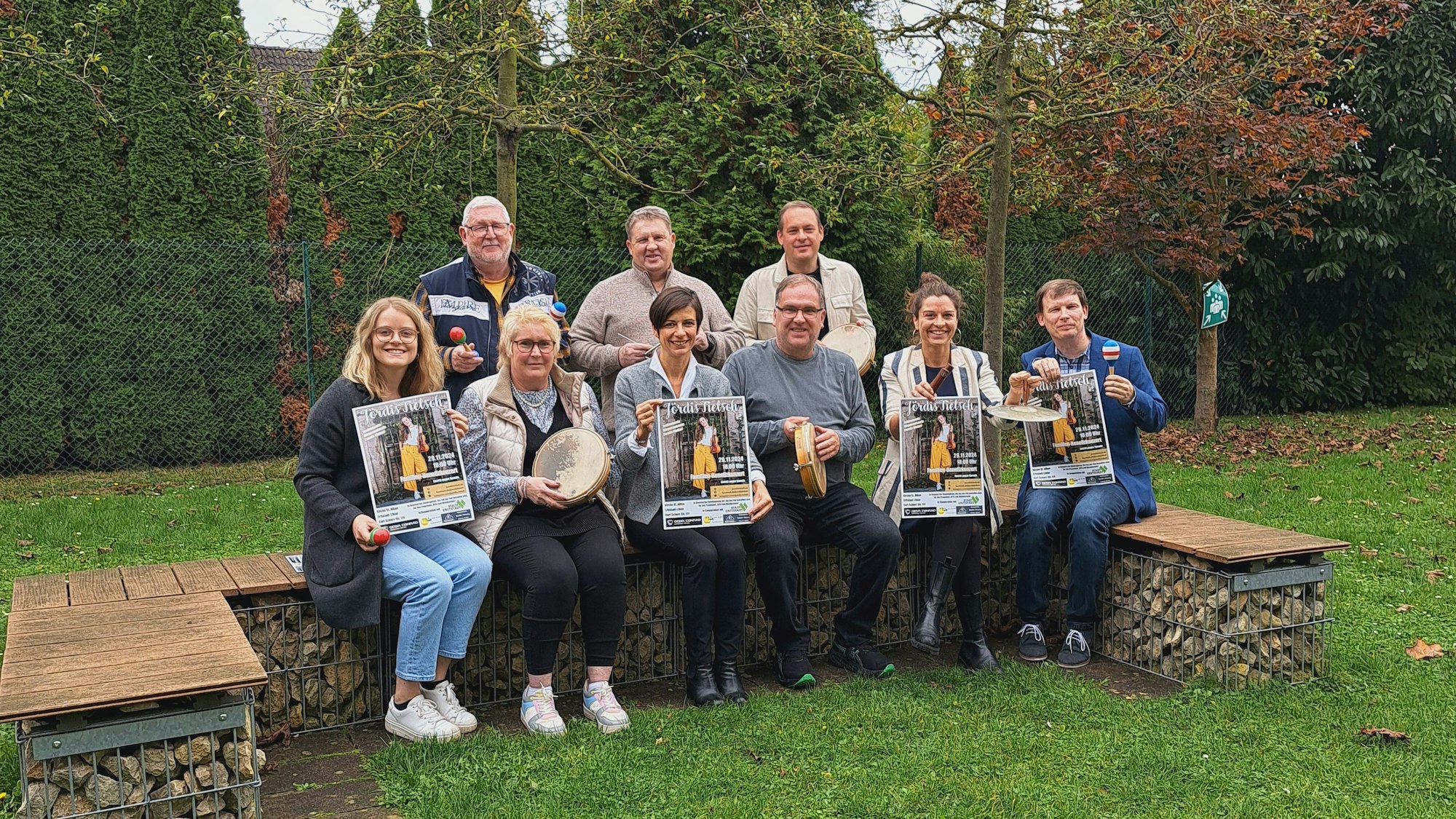 Neun Frauen und Männer werben mit Plakaten für ein Benefizkonzert.
