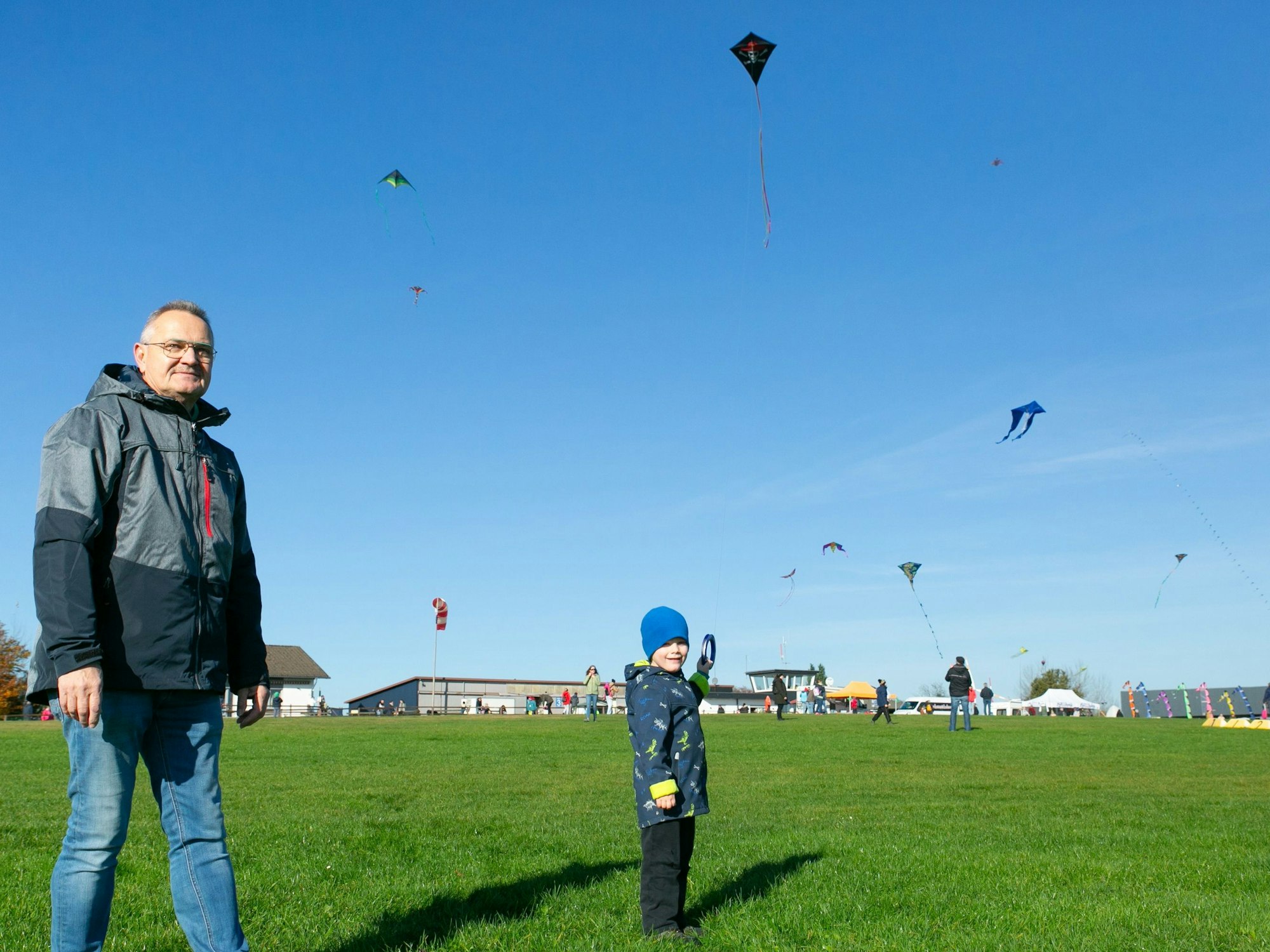 Ein Kind lässt, gemeinsam mit seinem Opa, einen Drachen steigen.