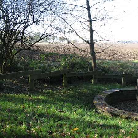 Blick auf einen frisch umgepflügten Acker mit dem Drei-Herren-Stein-Denkmal im Vordergrund.