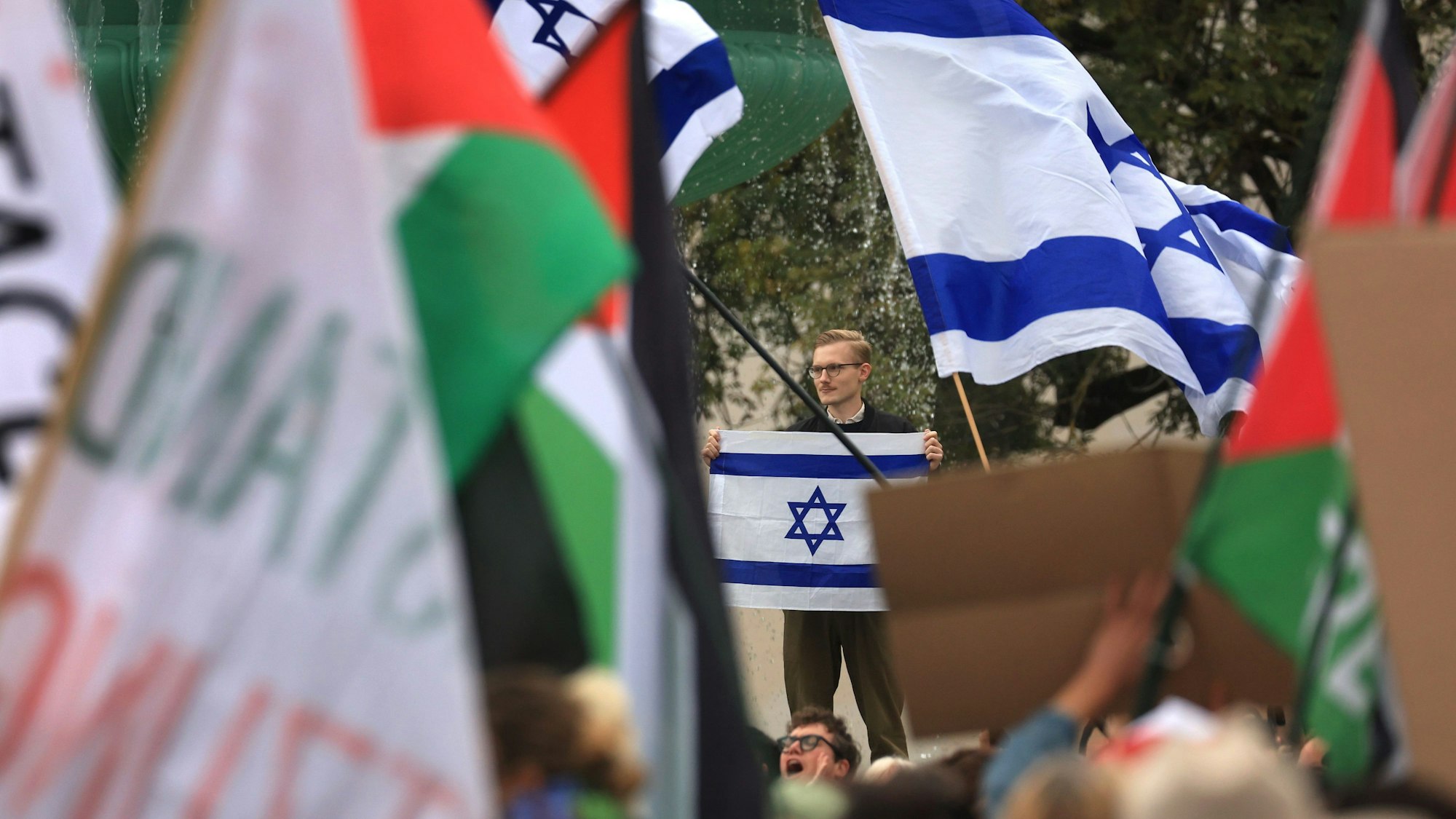 Demonstranten mit palästinensischen Fahnen ziehen bei einer propalästinensischen Demonstration an einer proisraelischen Gegendemonstration vorüber.