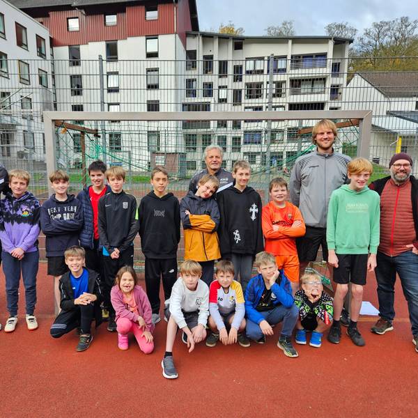 Die Ex-Fußballprofis Michael Klinkert und Marcel Witecek stehen mit den Kindern und zwei Lehrern an einem Tor.