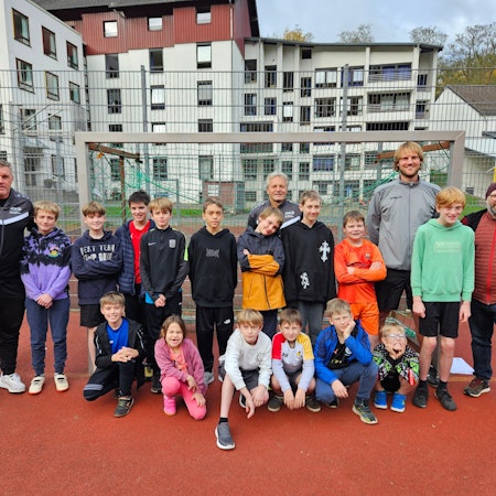 Die Ex-Fußballprofis Michael Klinkert und Marcel Witecek stehen mit den Kindern und zwei Lehrern an einem Tor.