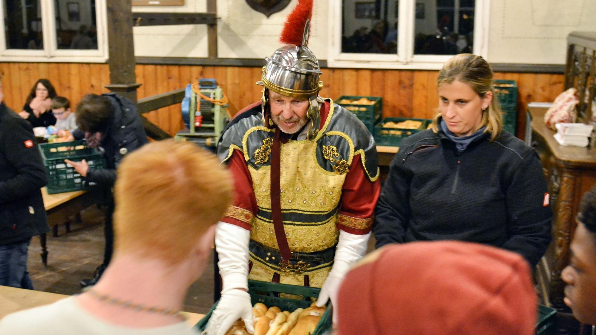 Ein Mann im St. Martin Kostüm verteilt Wecken.