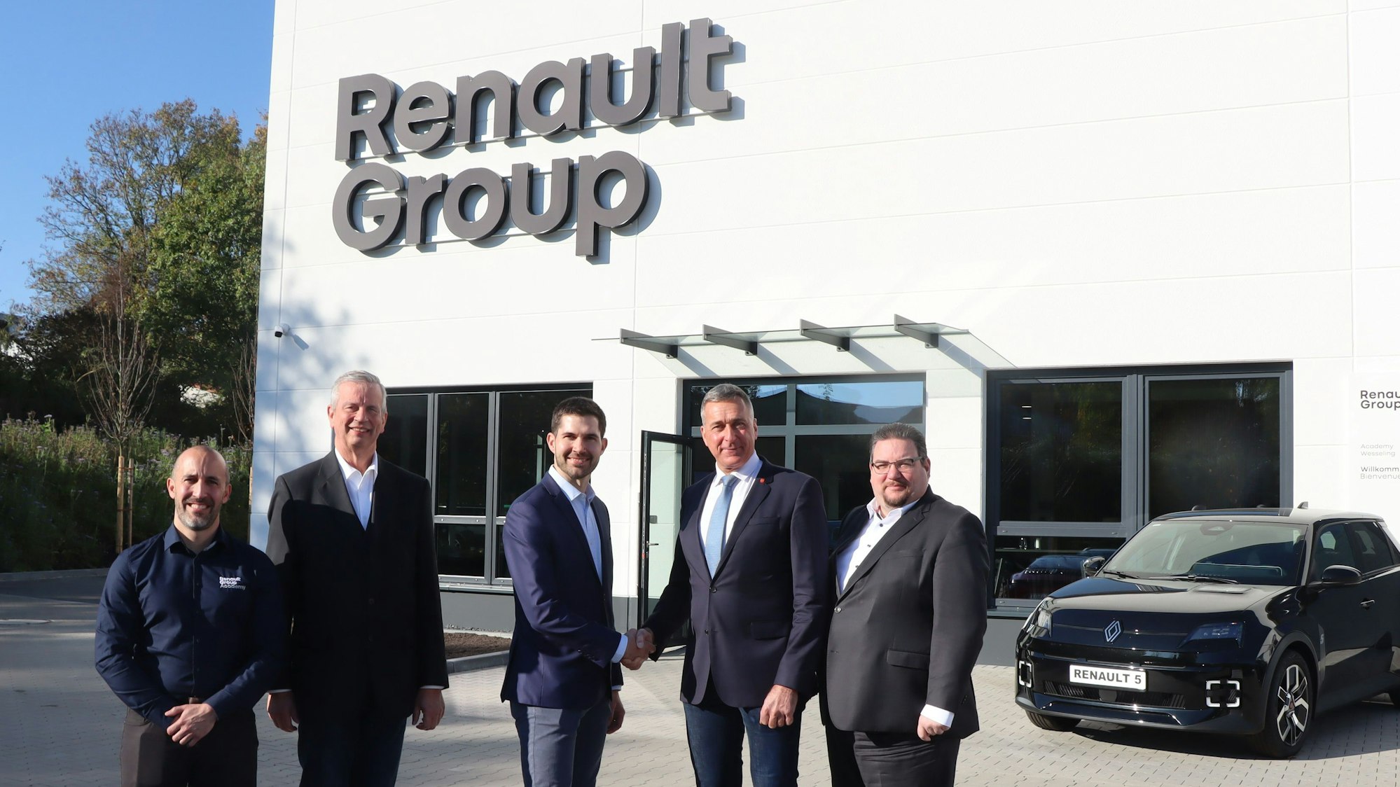 Das Foto zeigt fünf Männer in Anzeigen vor dem neuen Schulungszentrum der Renault Group. Im Hintergrund ein Auto.