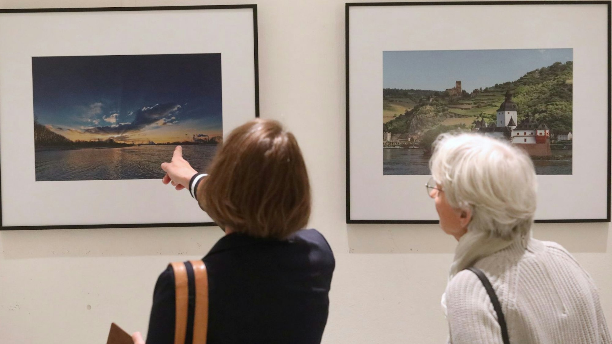Zwei Frauen betrachten zwei Fotografien, die zur Ausstellung gehören.