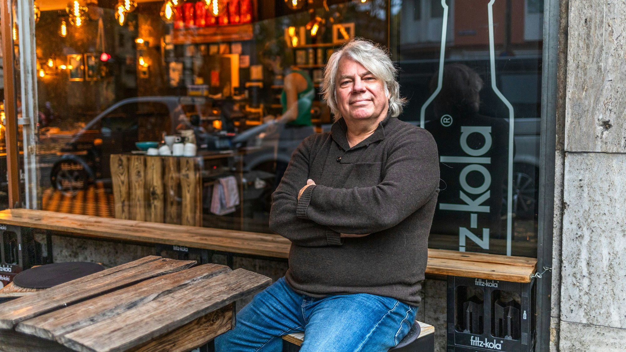 Peter Klöss sitzt vor dem Fenster eines Cafés.