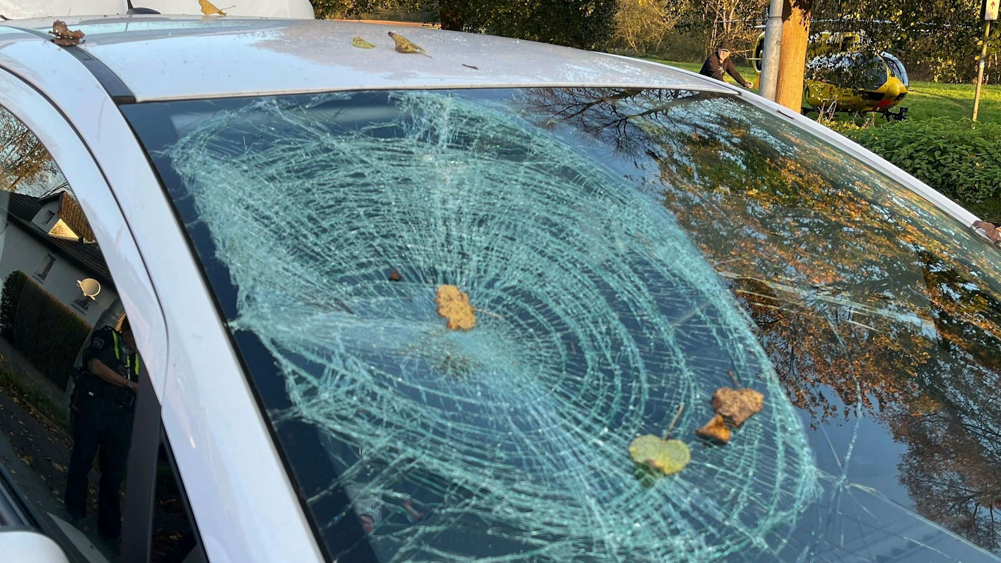 An einem Auto ist eine kaputte Windschutzscheibe zu sehen. Die Risse ziehen sich kreisförmig um den linken Teil der Scheibe.