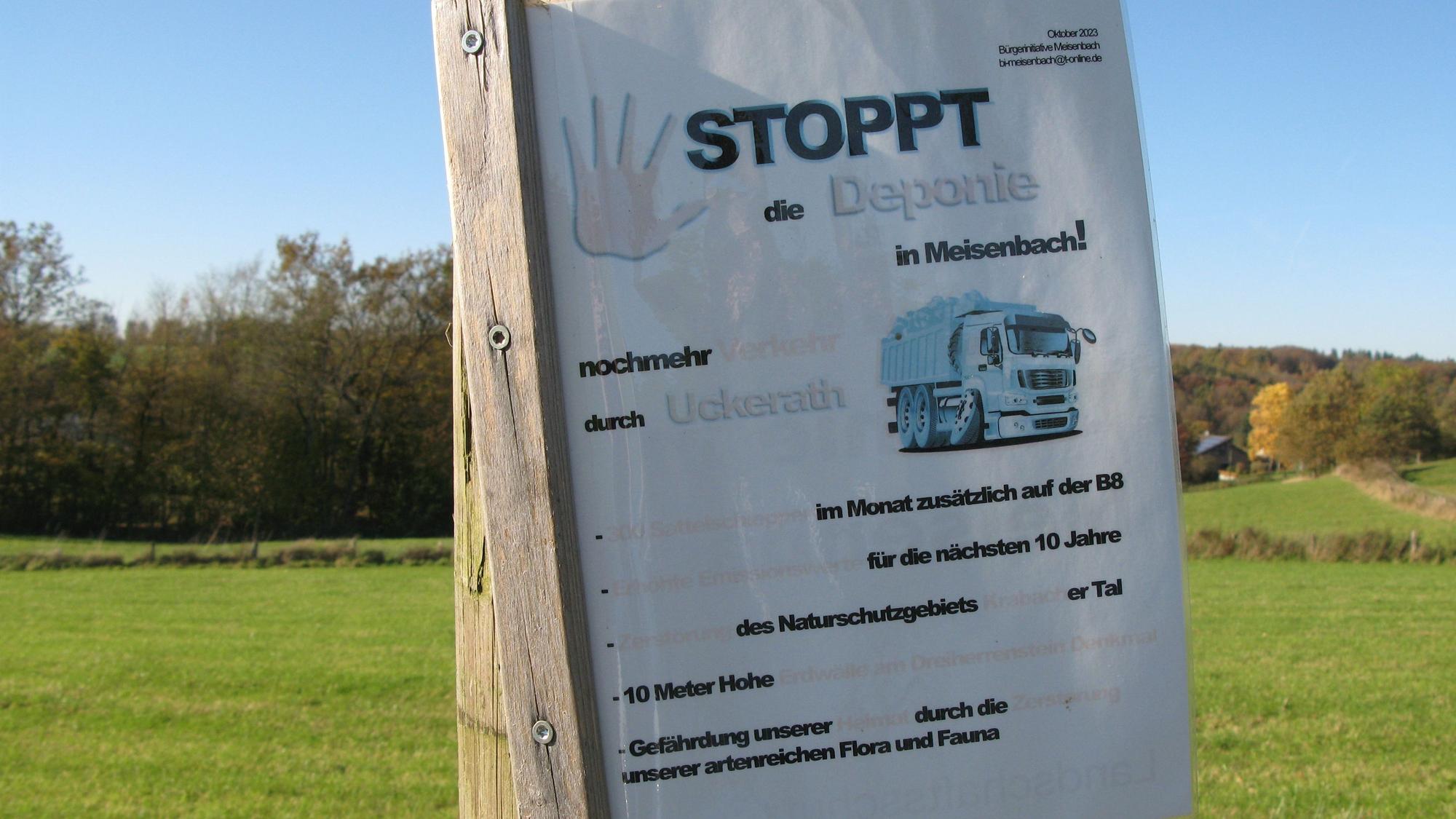 Ein Protestplakat an einem Holzmast mit der Überschrift „Stoppt die Deponie in Meisenbach“.