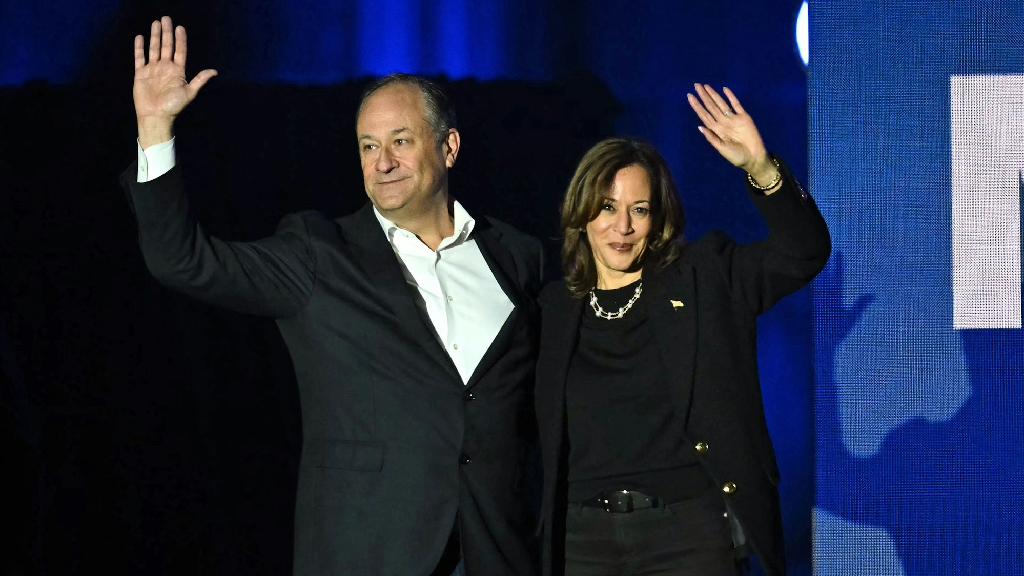 Die demokratische Kandidatin Kamala Harris und ihr Ehemann Doug Emhoff winken auf einer Veranstaltung ihren Unterstützern zu.