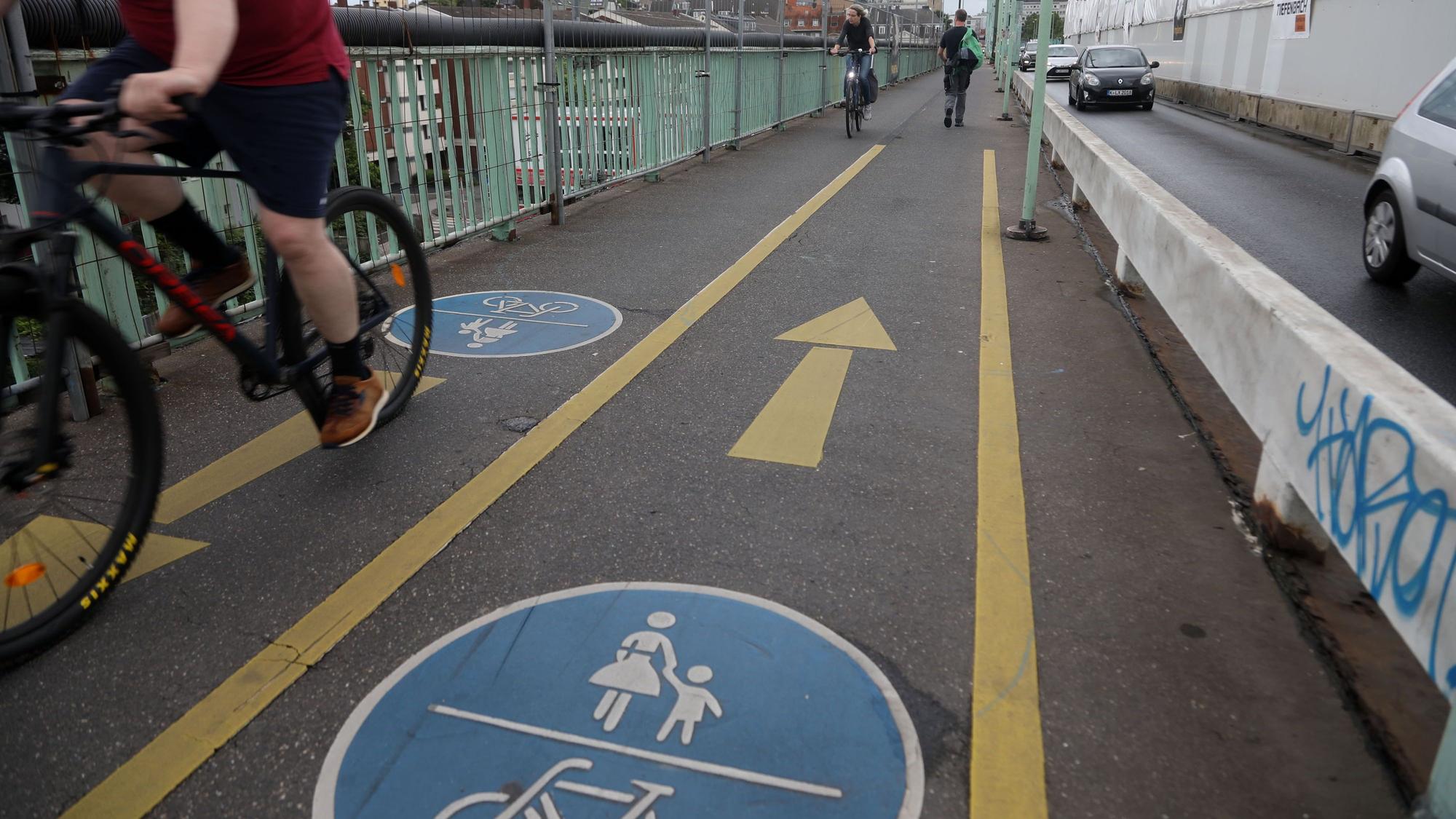Radfahrer fahren auf einer Fahrradspur auf der Mülheimer Brücke.