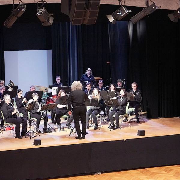 Ein Blasorchester spielt auf einer Bühne.