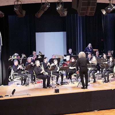 Ein Blasorchester spielt auf einer Bühne.