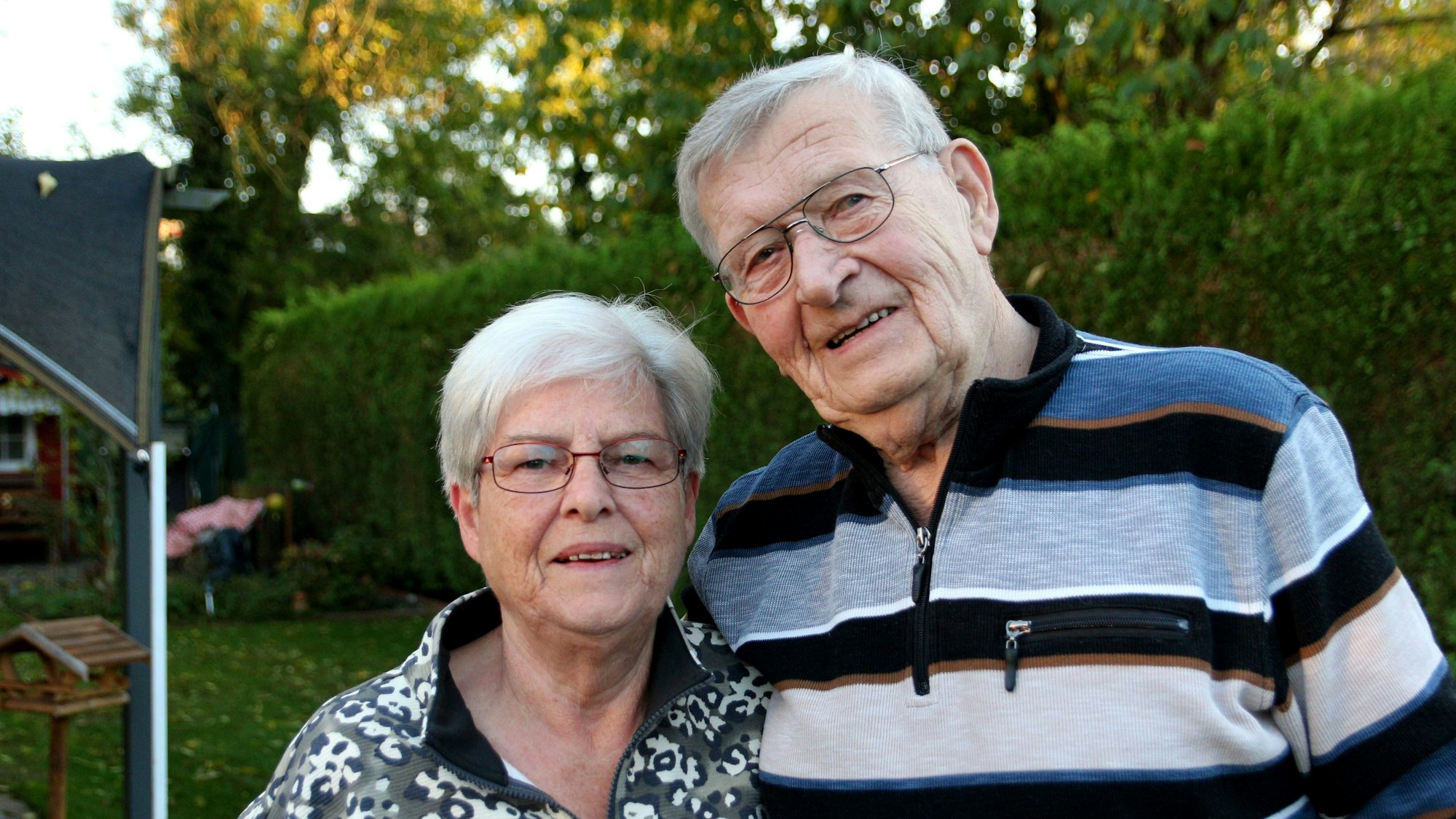 Das Ehepaar im Garten, beide lächeln in die Kamera.