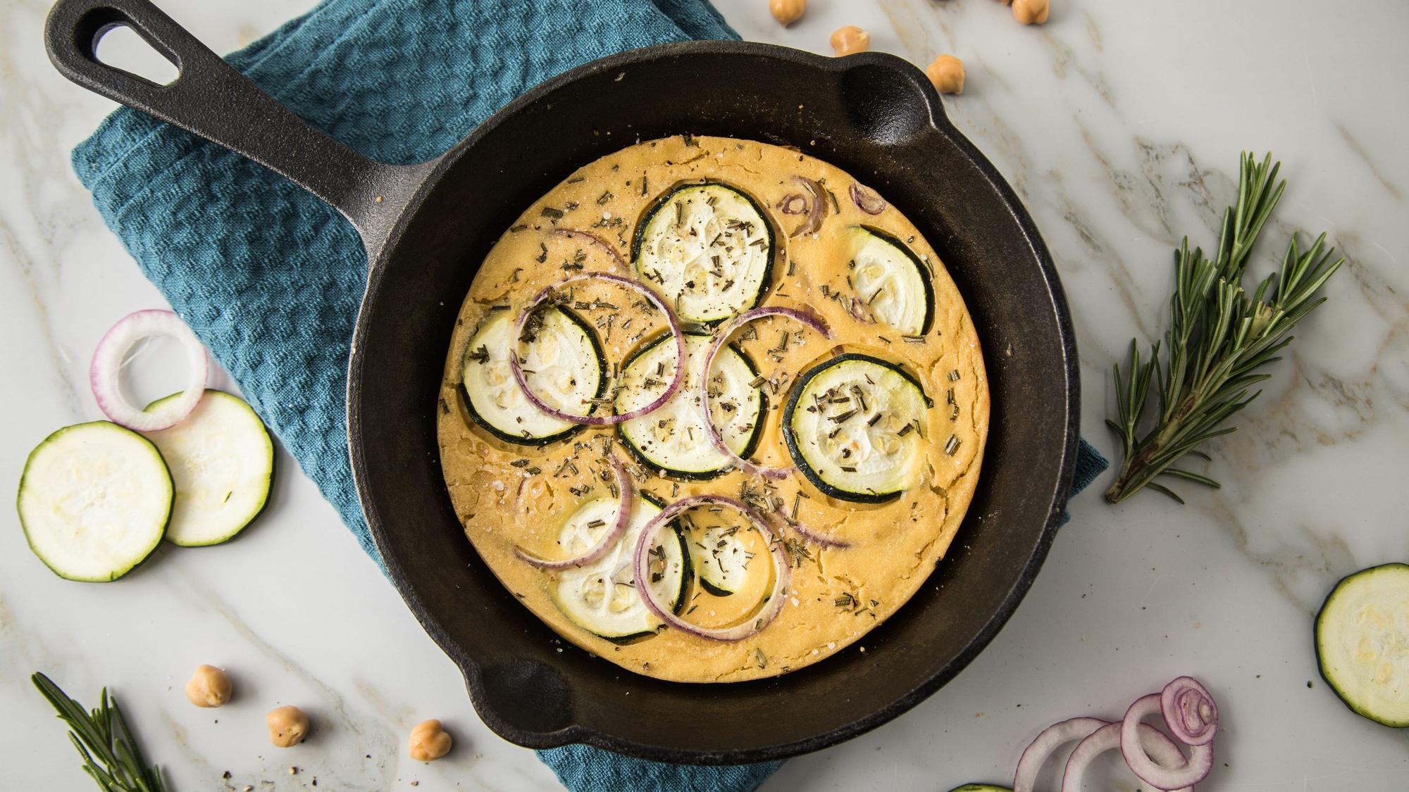Socca ist eine südfranzösische Fladenbrot-Spezialität. Hier ist die Socca-Pizza aus Kichererbsenmehl mit Zucchini, Rosmarin und roten Zwiebeln belegt.