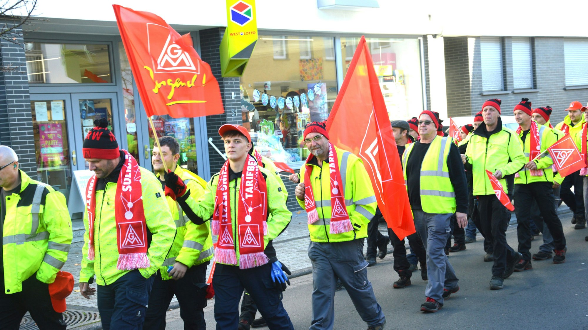 Blick auf Streikende, die gelbe Jacken und IG-Metall-Fahnen tragen.