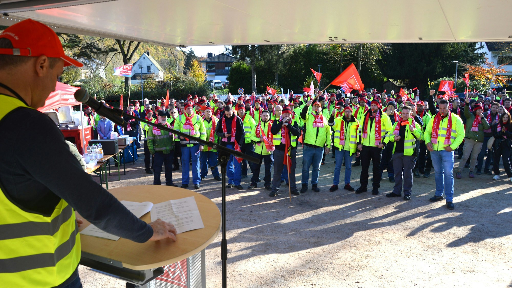 Michael Korsmeier steht auf einem Hänger und ist seitlich von hinten zu sehen. Davor stehen die Streikenden.