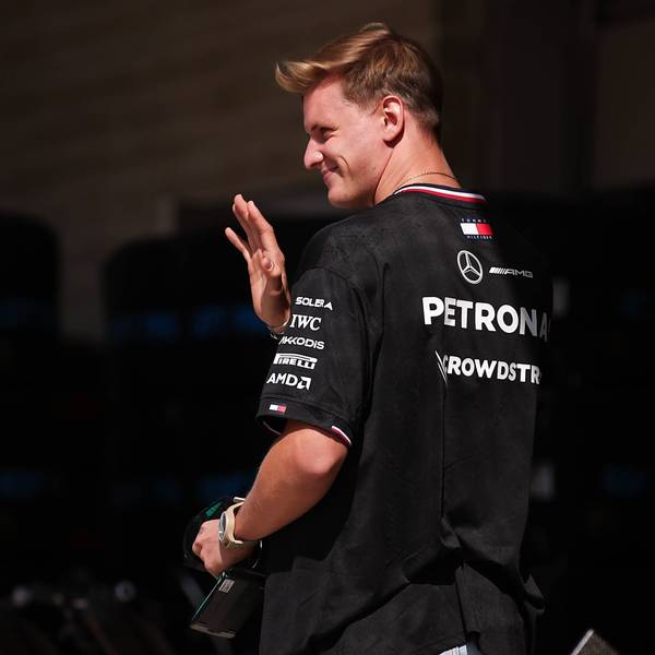 Mick Schumacher geht durch die Boxengasse und winkt.