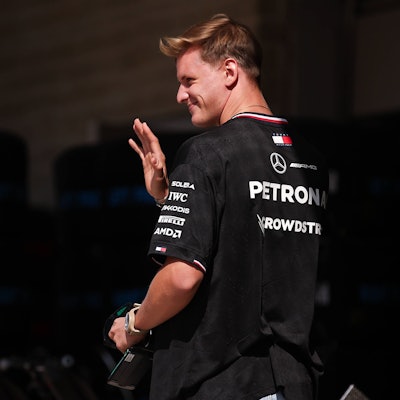 Mick Schumacher geht durch die Boxengasse und winkt.
