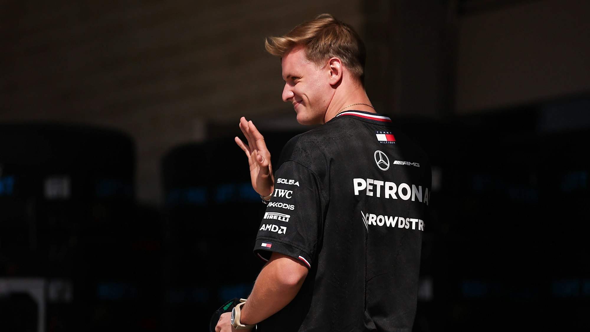 Mick Schumacher geht durch die Boxengasse und winkt.