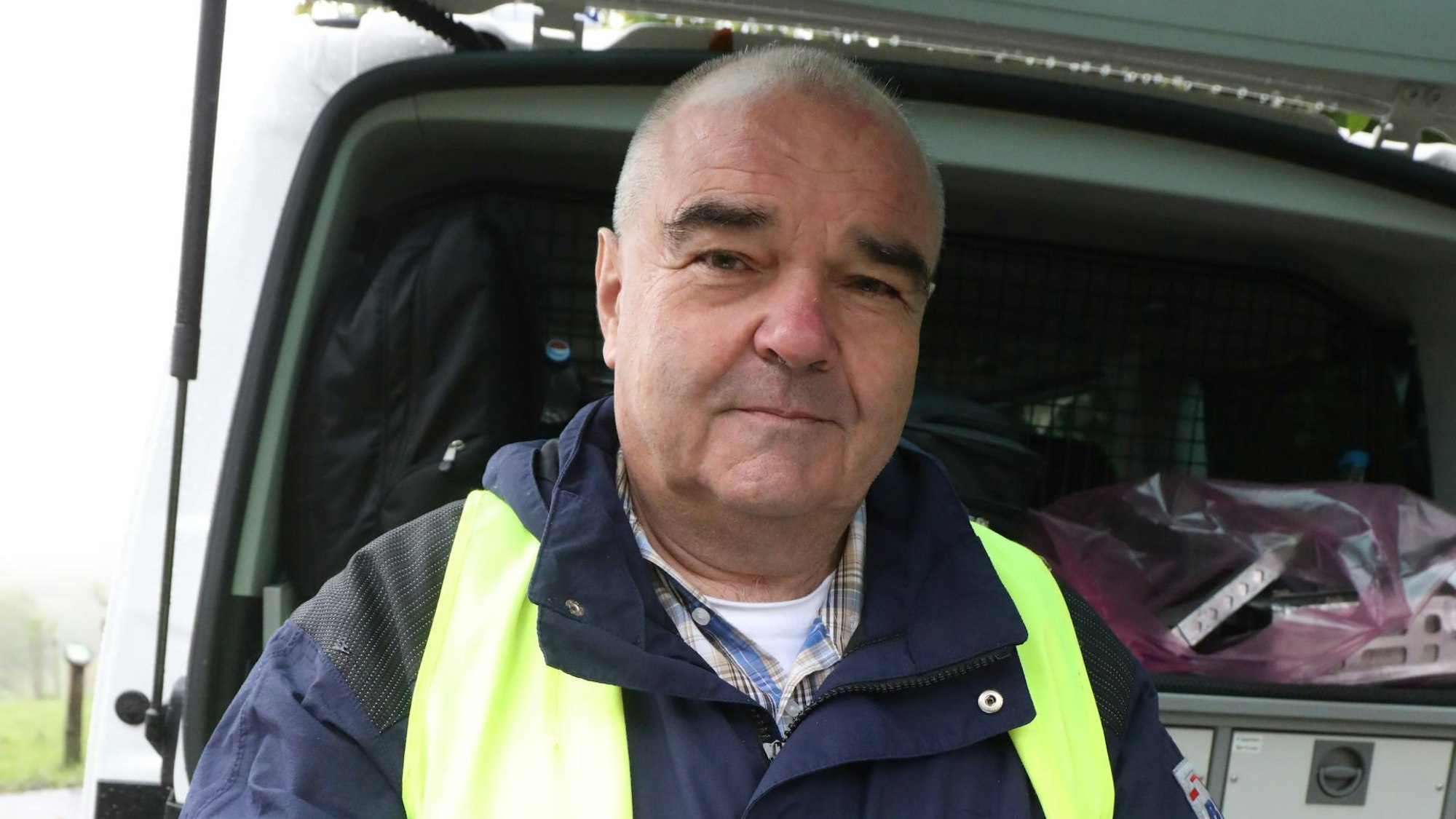 Ein Mann steht vor der geöffneten Heckklappe eines Kleintransporters.