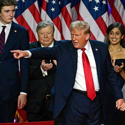 TOPSHOT - Former US President and Republican presidential candidate Donald Trump gestures at supporters after speaking as he holds hands with former US First Lady Melania Trump during an election night event at the West Palm Beach Convention Center in West Palm Beach, Florida, early on November 6, 2024. Republican former president Donald Trump closed in on a new term in the White House early November 6, 2024, just needing a handful of electoral votes to defeat Democratic Vice President Kamala Harris. (Photo by Jim WATSON / AFP)