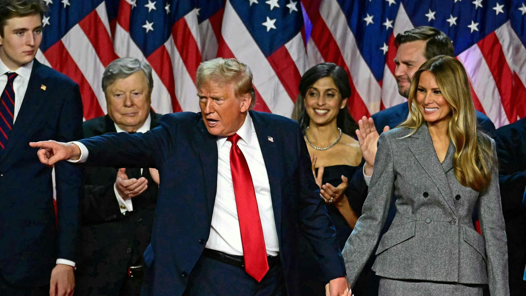 TOPSHOT - Former US President and Republican presidential candidate Donald Trump gestures at supporters after speaking as he holds hands with former US First Lady Melania Trump during an election night event at the West Palm Beach Convention Center in West Palm Beach, Florida, early on November 6, 2024. Republican former president Donald Trump closed in on a new term in the White House early November 6, 2024, just needing a handful of electoral votes to defeat Democratic Vice President Kamala Harris. (Photo by Jim WATSON / AFP)