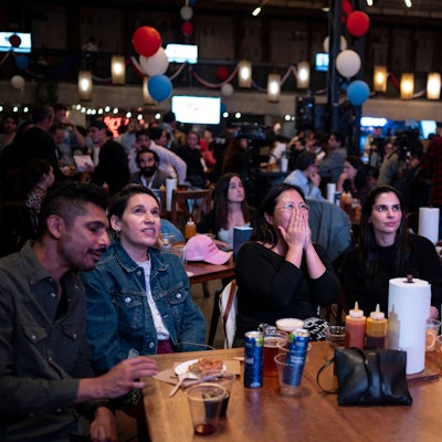 Menschen verfolgen in einem Restaurant die Berichterstattung über die US-Wahl 2024.
