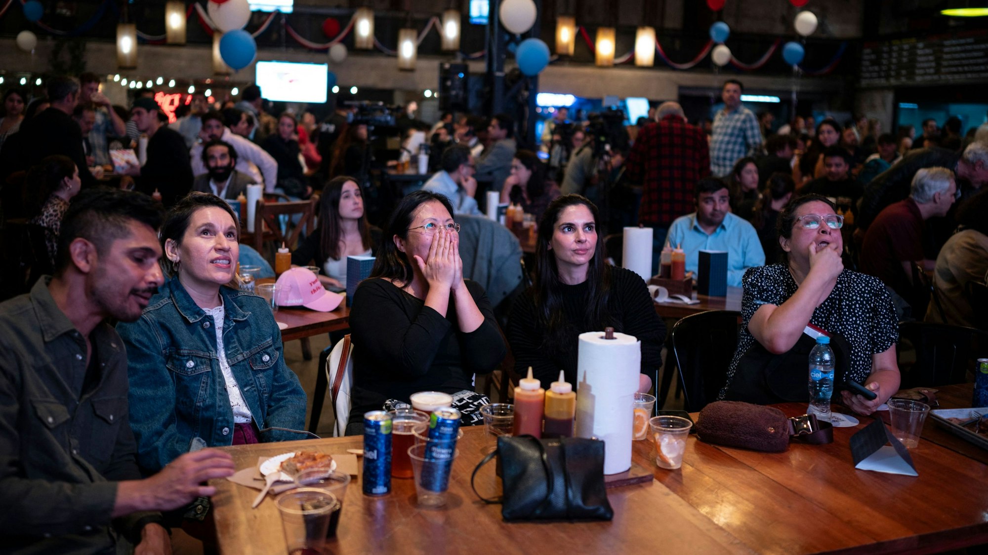Menschen verfolgen in einem Restaurant die Berichterstattung über die US-Wahl 2024.