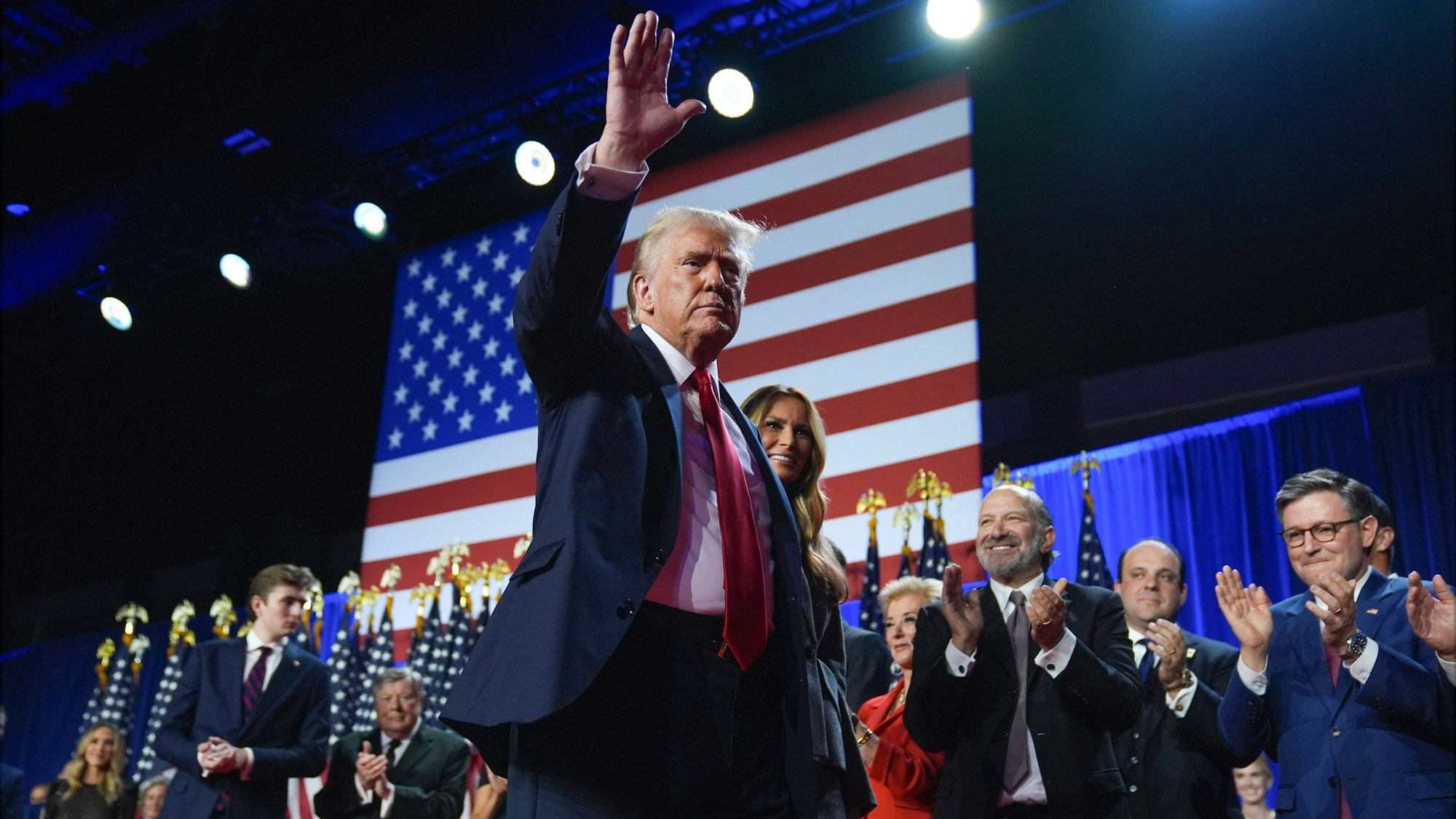 06.11.2024, USA, West Palm Beach: Der republikanische Präsidentschaftskandidat und frühere Präsidentschaftskandidat Donald Trump winkt, während er mit der ehemaligen First Lady Melania Trump bei einer Wahlparty im Palm Beach Convention Center am Mittwoch, 6. November 2024, in West Palm Beach, Florida, über die Bühne geht.