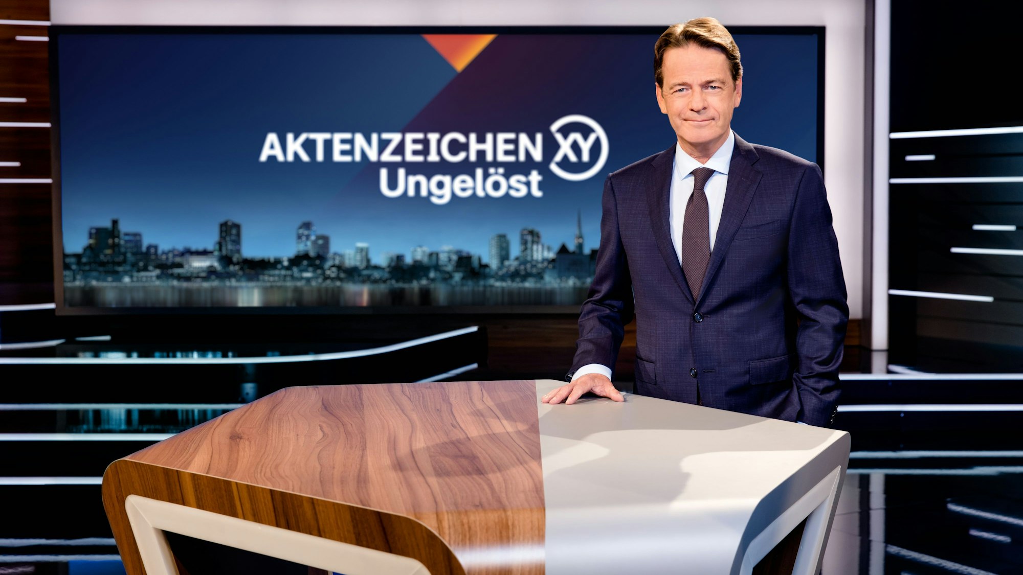 Moderator Rudi Cerne steht vor dem Tresen im Studio der TV-Sendung „Aktenzeichen XY... ungelöst“.