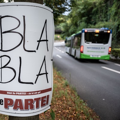 Ein Plakat zur Kommunalwahl in Nordrhein-Westfalen von ·Die Partei· mit der Aufschrift ·Bla Bla· ist auf dem Mittelstreifen einer Strasse an einem Baum befestigt.