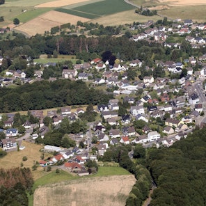 Ein Luftbild von Odenthal-Blecher. Man sieht den zentralen Kreisverkehr, links davon die Bergstraße und im unteren Bildteil die Serperntinen nach Altenberg.