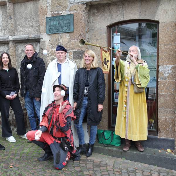 Eine Gruppe vom Menschen, zum Teil in mittelalterlichen Kostümen. Im Vordergrund ein Jongleur mit Bällen.