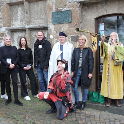 Eine Gruppe vom Menschen, zum Teil in mittelalterlichen Kostümen. Im Vordergrund ein Jongleur mit Bällen.