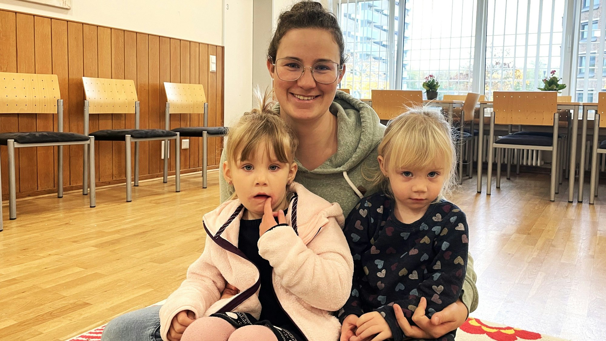 Die 28-jährige Mutter Sonja M. sitzt mit ihren Töchtern Amelie (4) und Clara (2) auf dem Holzboden eines Musikraums.