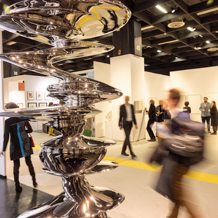 Besucher gehen auf der Art Cologne Kunstmesse an der Skulptur aus Edelstahl von Tony Cragg mit dem Titel Elliptical Columna vorbei.