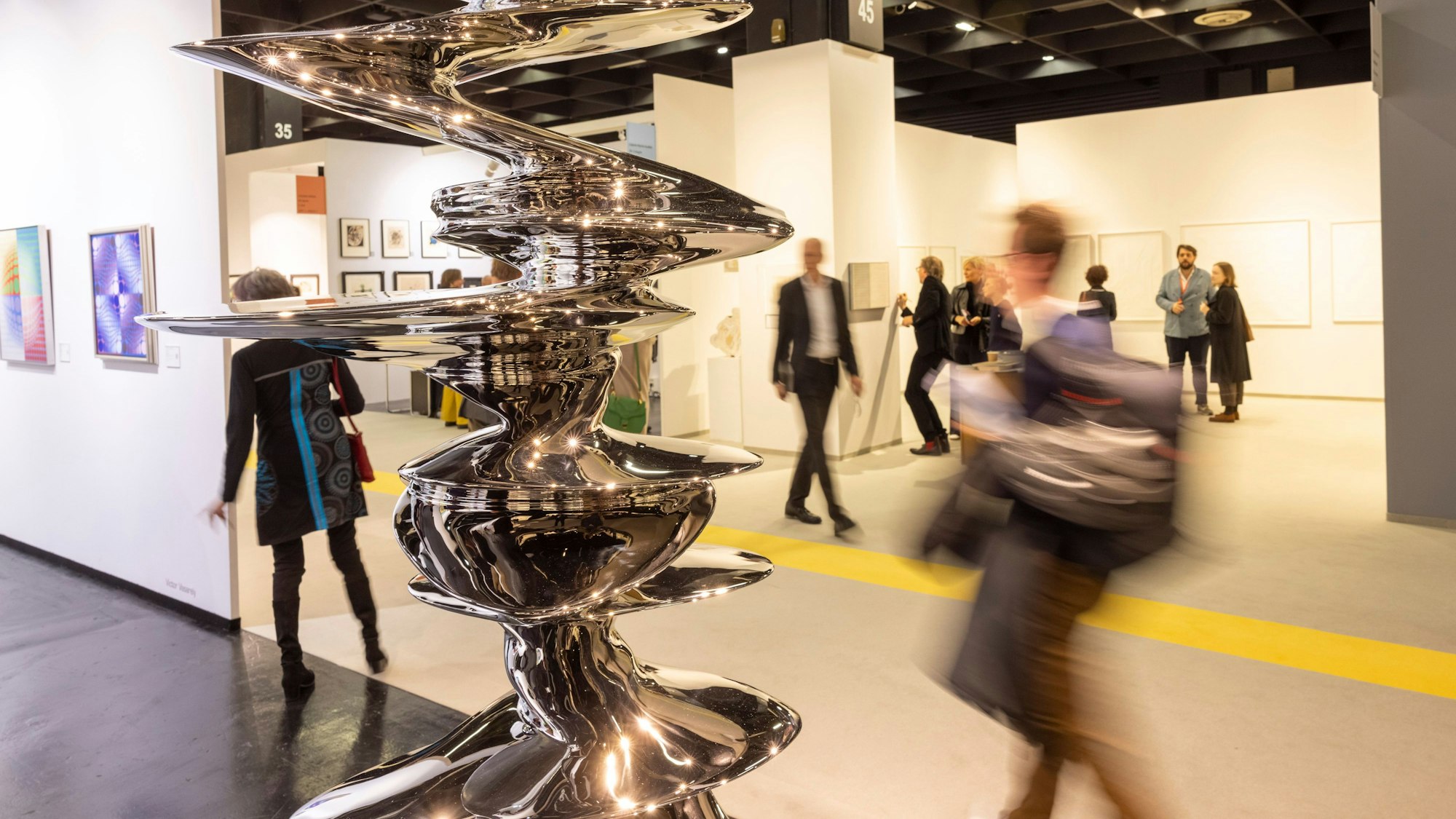 Besucher gehen auf der Art Cologne Kunstmesse an der Skulptur aus Edelstahl von Tony Cragg mit dem Titel Elliptical Columna vorbei.